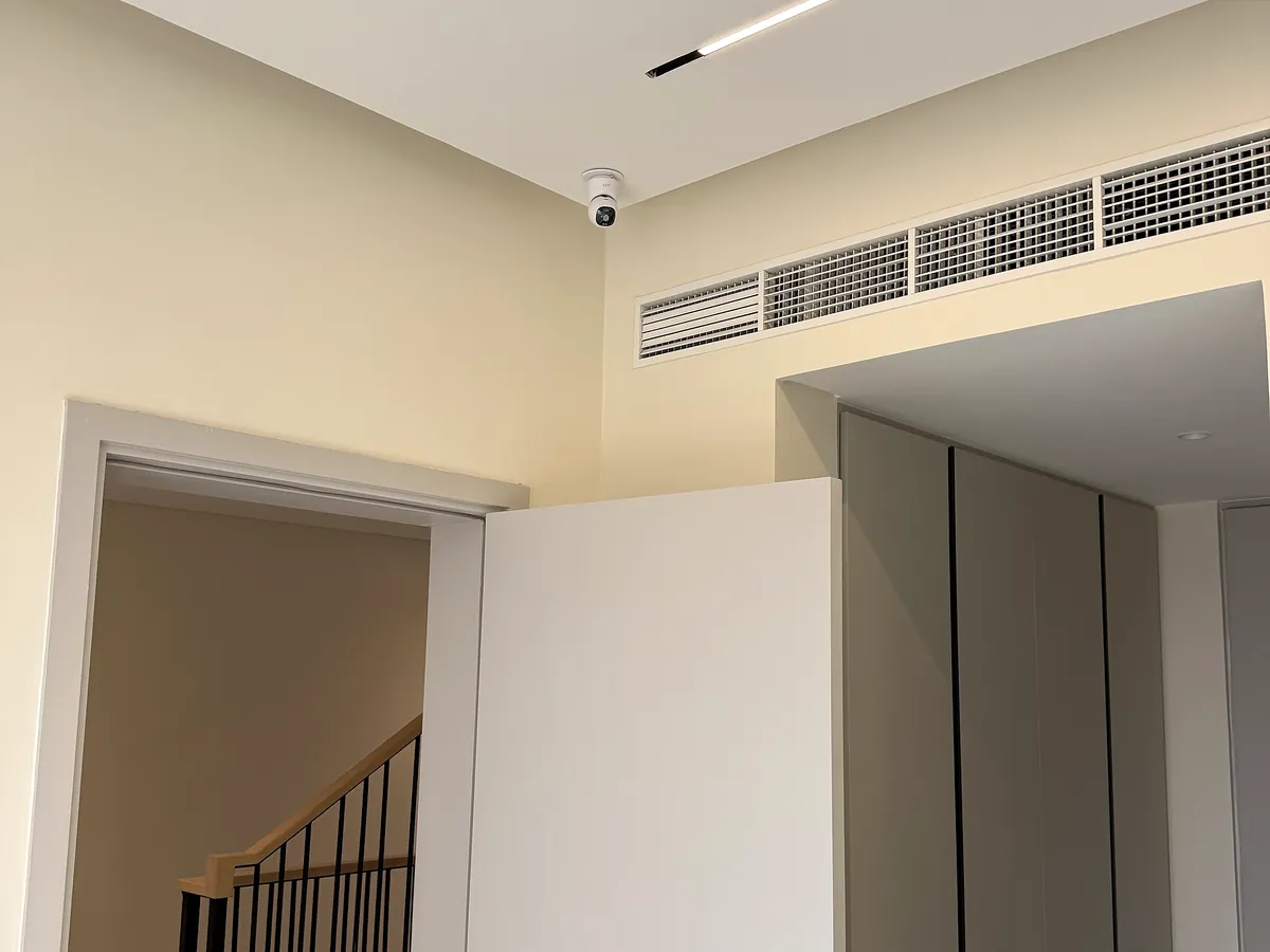 Discreet ceiling-mounted dome camera covering a villa stairwell and hallway
