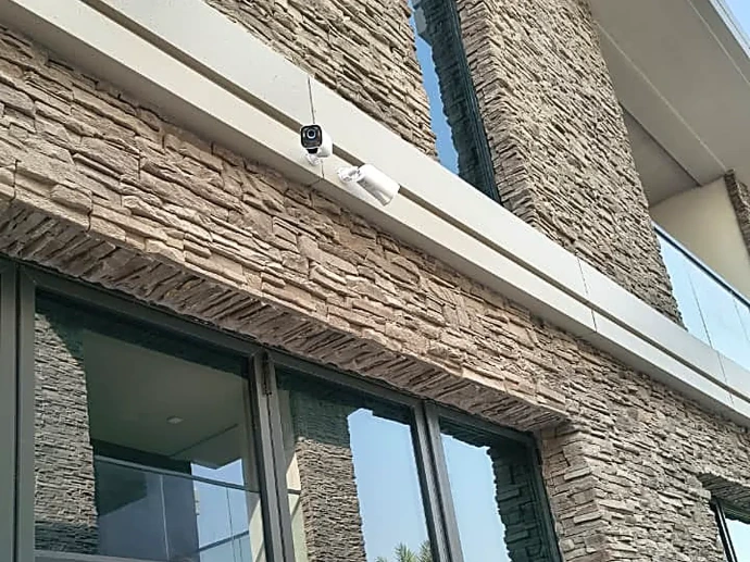 Security cameras mounted on the soffit of a stone-clad Dubai villa